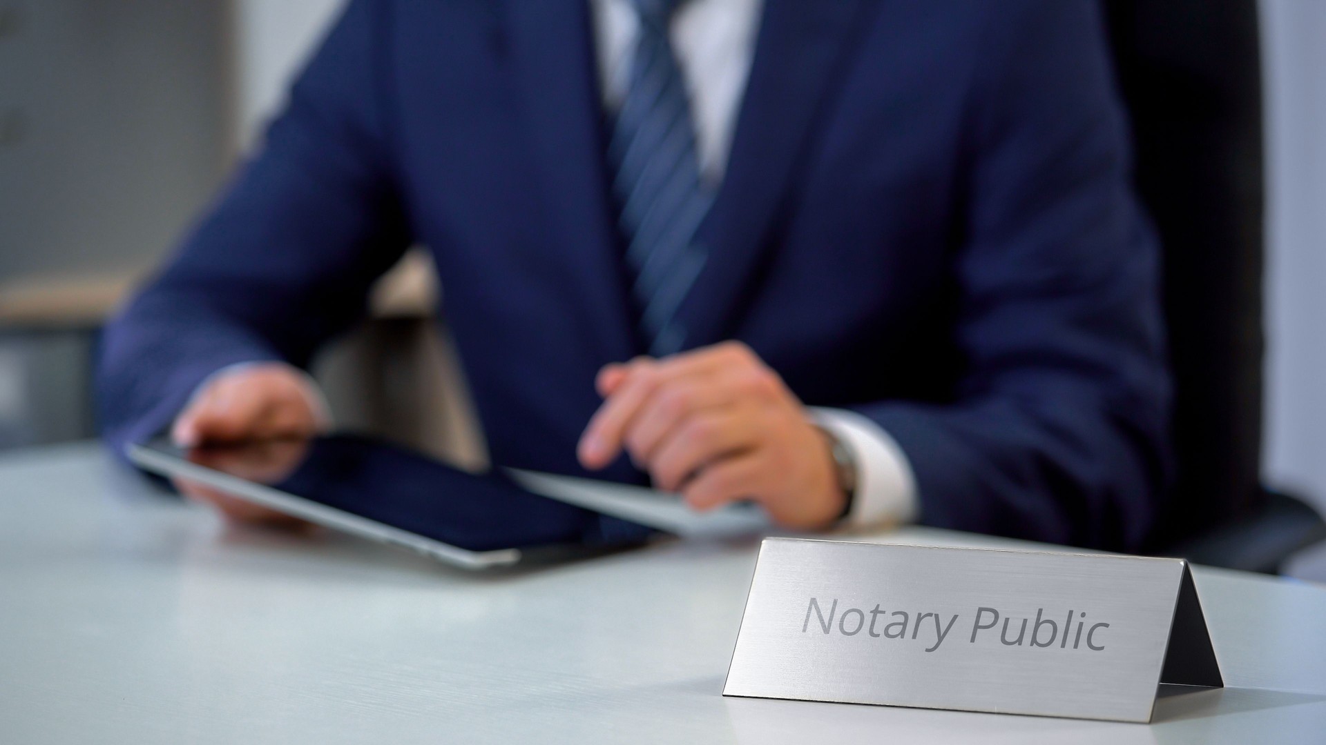 Male notary public viewing files on tablet, checking documents for notarization